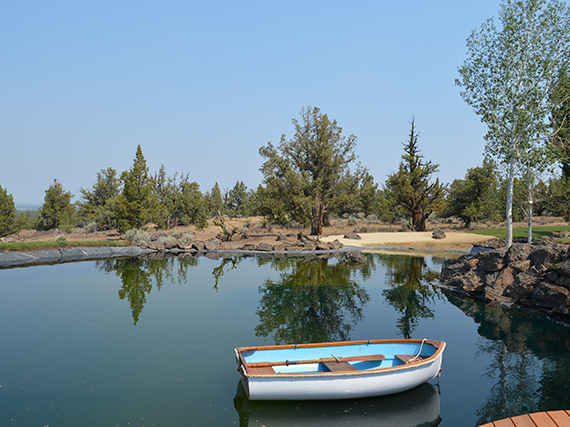 Recreational pond, swim pond, kayak pond with white sandy beach for sunbathing, mossy boulders line the pond edge.